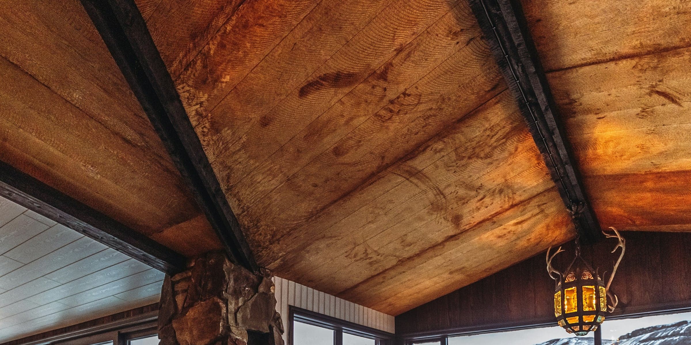 A stone hearth under a timber ceiling, with a wall of glass onto the snow line.